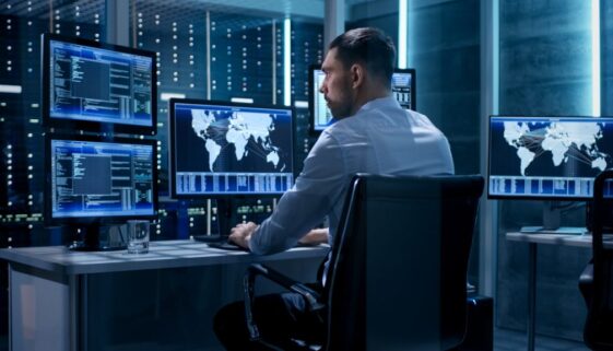 Technical Controller Working at His Workstation with Multiple Displays. Displays Show Various Technical Information. He's Alone in System Control Center.