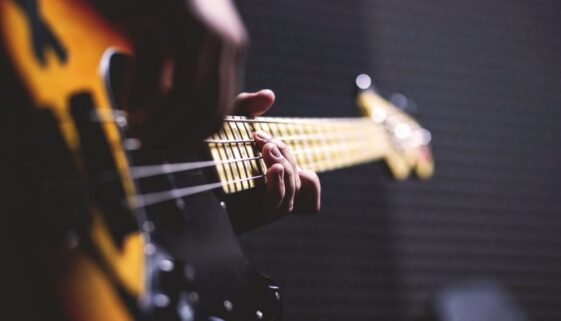 person-playing-sun-burst-electric-bass-guitar-in-bokeh-96380