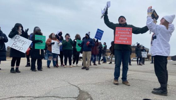 Professor Dr. Darryl Whetter leads the protesters in song at Université Sainte-Anne