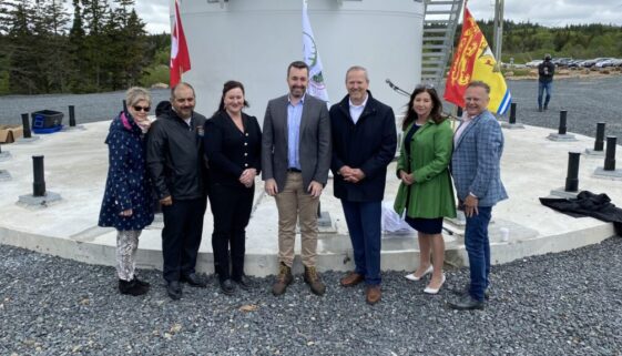 Officials pose for a photo in front of a wind turbine during the grand opening of the Burchill Wind Energy project in Saint John on June 6, 2023. Image Brad Perry